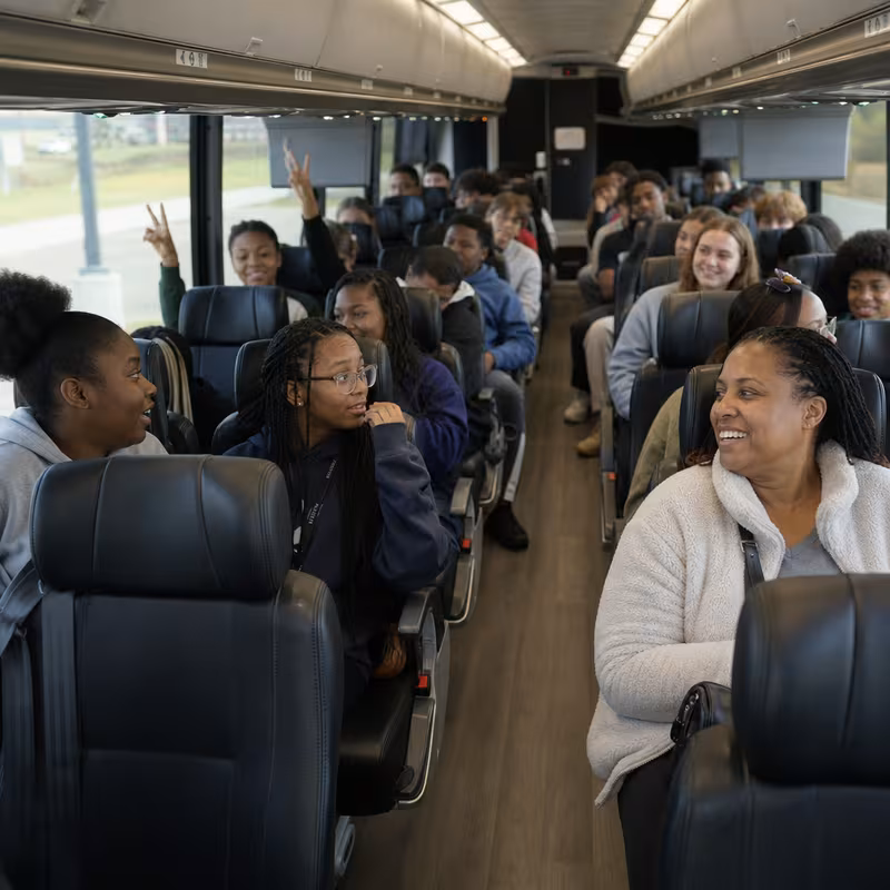 Group boarding a white charter bus for School Transportation transportation in Rochester