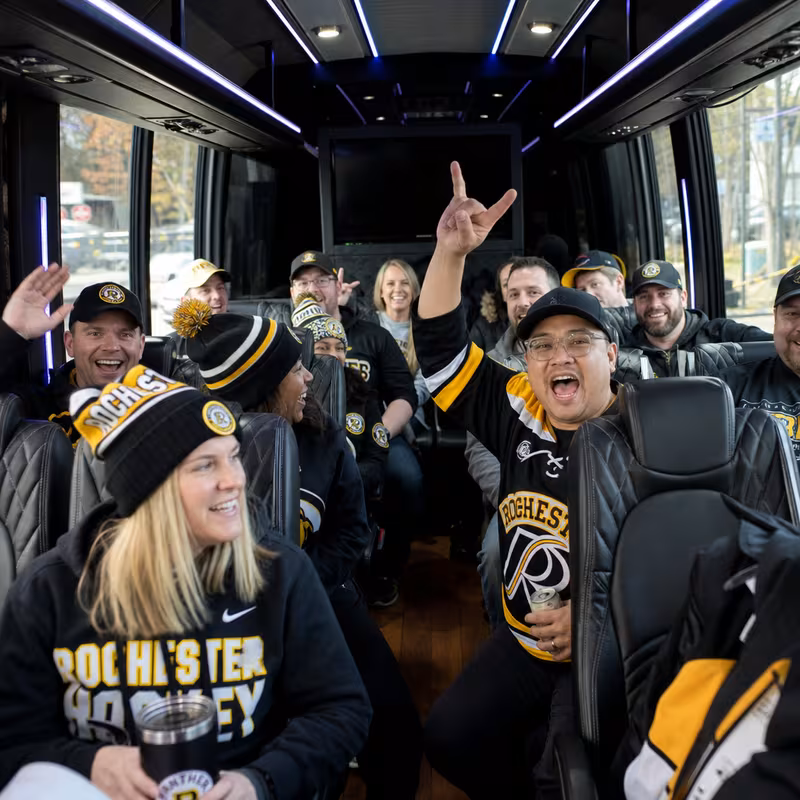 Group boarding a white charter bus for Sporting Event Transportation transportation in Rochester